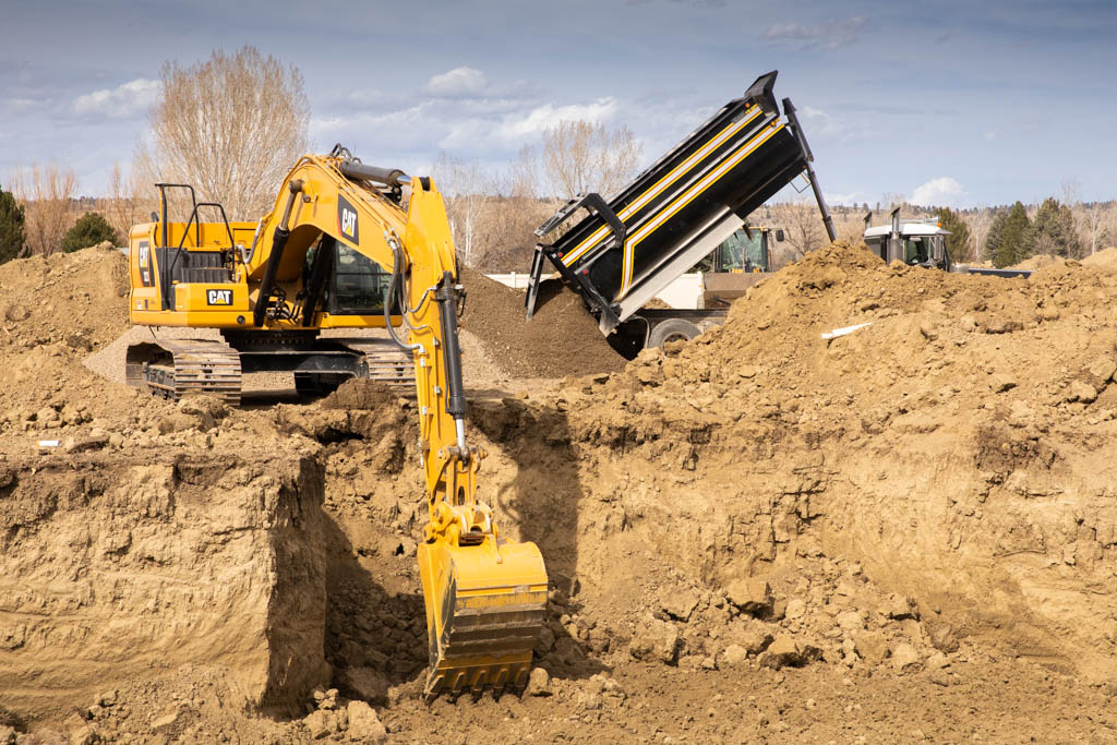 Excavator digging a trench during drain field repair