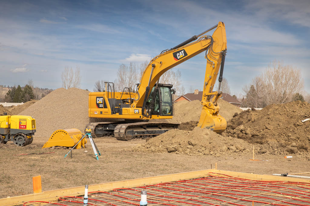 Excavator and survey equipment at an engineered building site