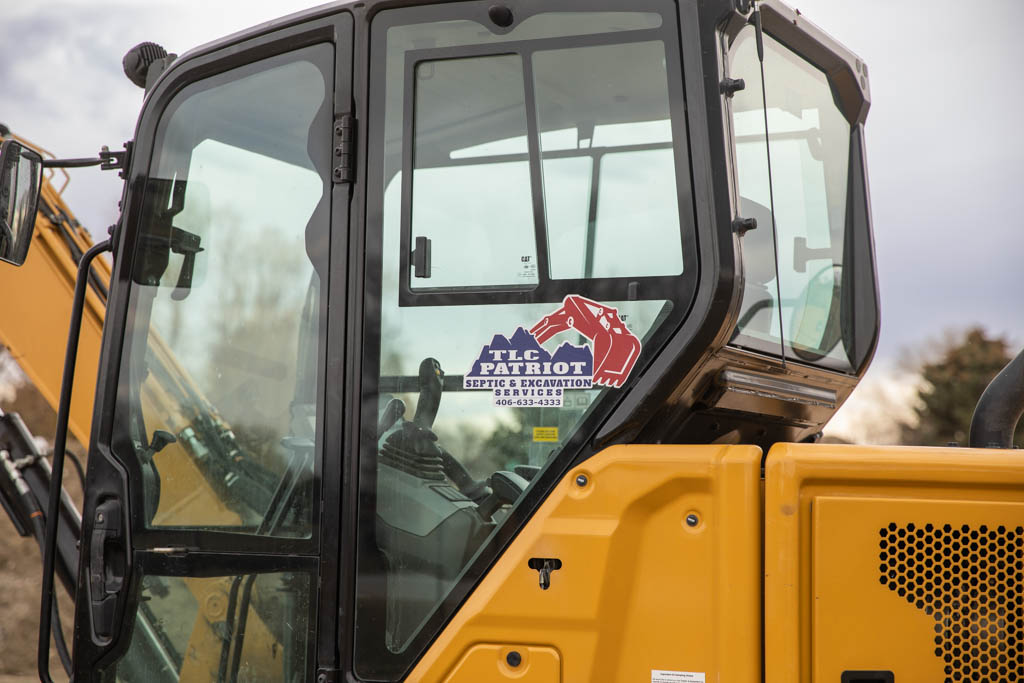 Equipment cab displaying the TLC Patriot Septic & Excavation logo